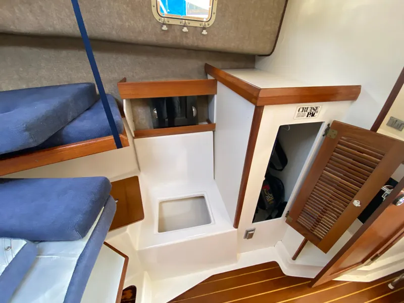 Slide: The Image of 1986 Luhrs Alura cabin interior with wooden accents and blue cushions. - 17