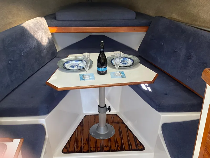Slide: The Image of 1986 Luhrs Alura cabin interior with dining setup, featuring blue seating and a central table. - 21