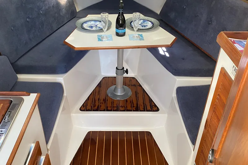 Slide: The Image of 1986 Luhrs Alura cabin interior with dining setup, featuring wood accents and cozy seating. - 22