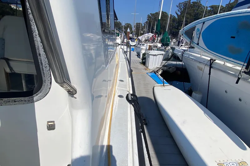 Slide: The Image of 1986 Luhrs Alura docked at marina, side view with nearby boats and paddleboard. - 8