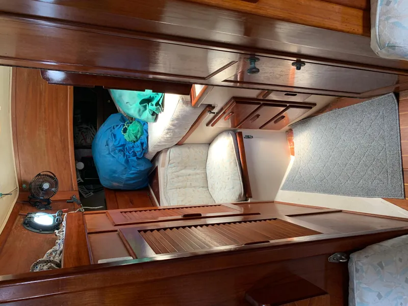 Slide: The Image of Interior of 1988 Pacific Seacraft Cutter, featuring wooden cabinetry and cozy sleeping area. - 10