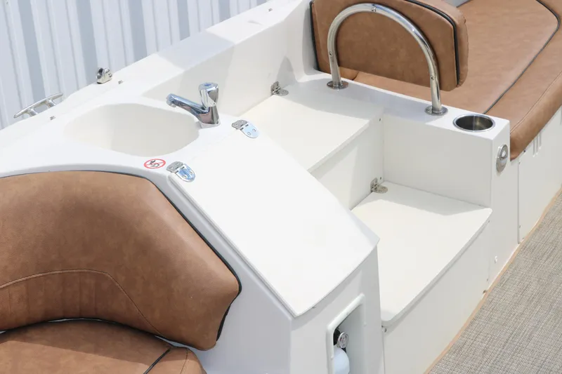 Slide: The Image of 2020 Stingray 212SC boat interior with brown seating and a small sink. - 10