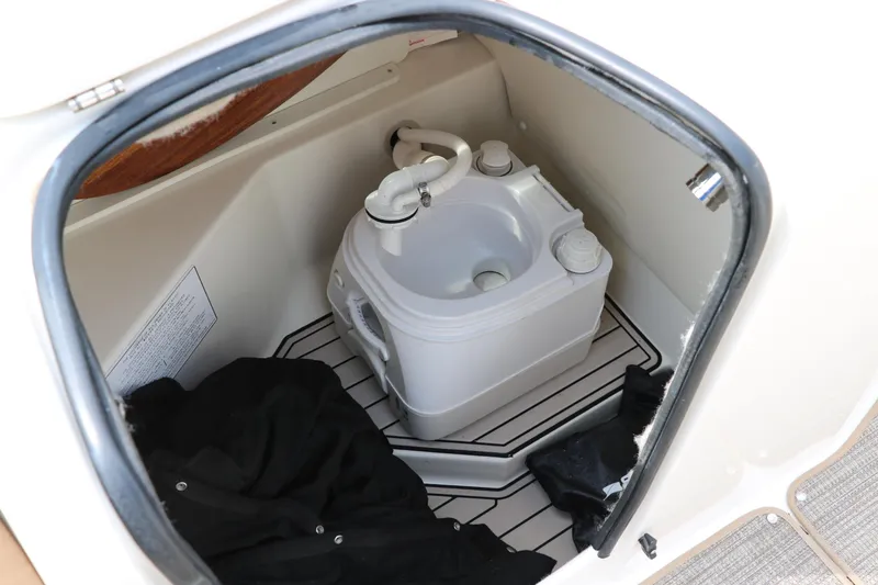 Slide: The Image of 2020 Stingray 212SC boat interior with portable toilet and storage area. - 18