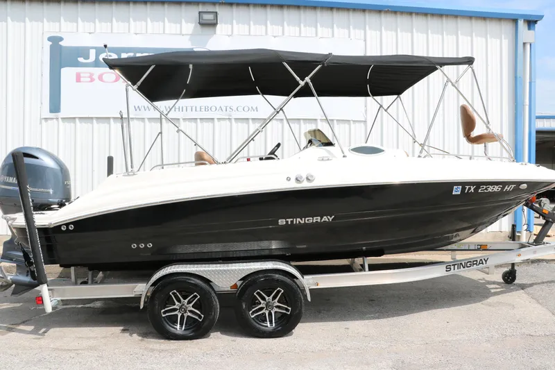 Slide: The Image of 2020 Stingray 212SC boat on trailer with black canopy. - 2