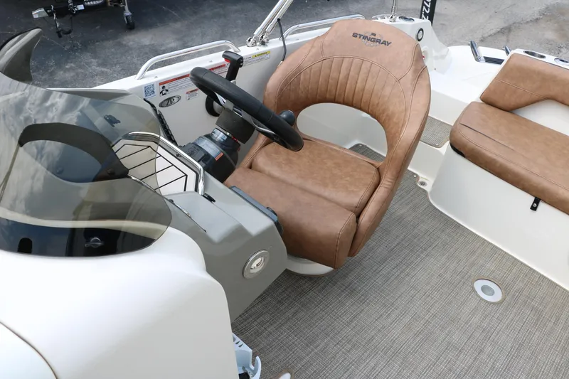 Slide: The Image of 2020 Stingray 212SC boat cockpit with tan captain's chair and steering wheel. - 26