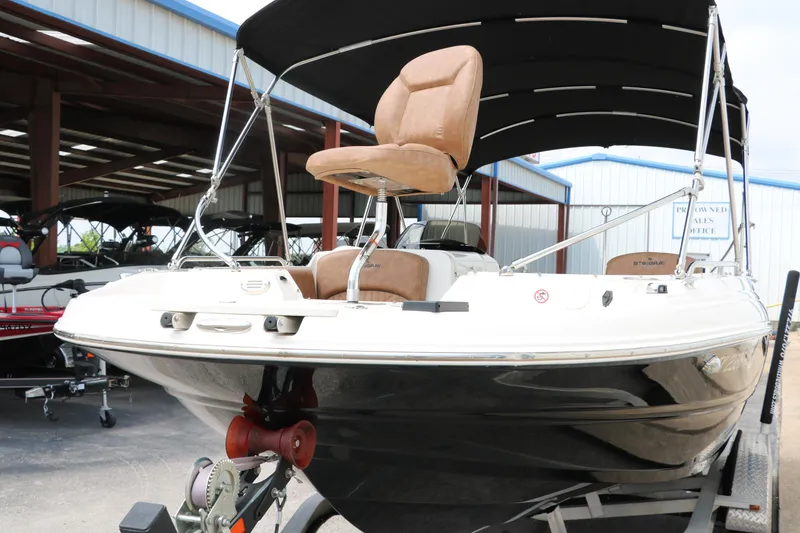 Slide: The Image of 2020 Stingray 212SC boat with canopy and tan seating in a storage facility. - 42