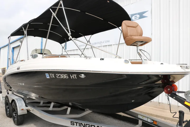 Slide: The Image of 2020 Stingray 212SC boat on trailer with black hull and canopy. - 45