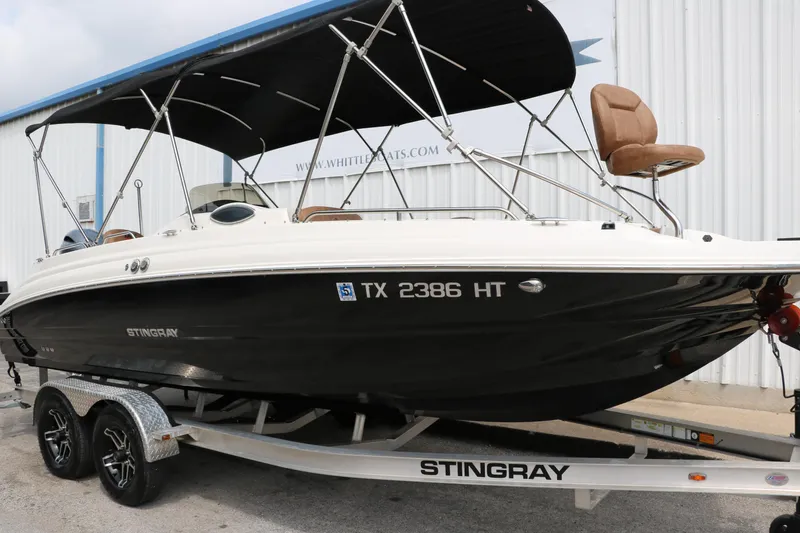 Slide: The Image of 2020 Stingray 212SC boat on trailer with black hull and bimini top. - 46