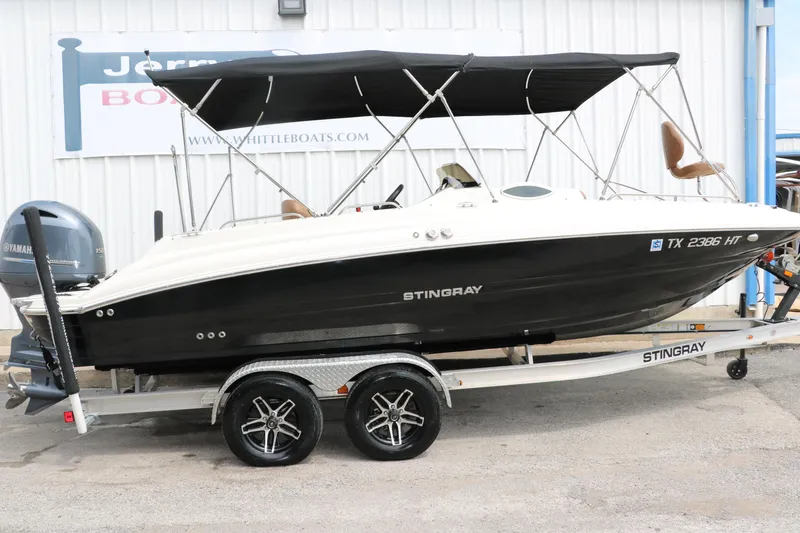Slide: The Image of 2020 Stingray 212SC boat on trailer with black hull and bimini top. - 48