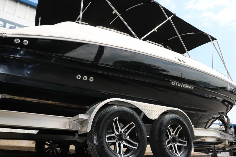 Slide: The Image of 2020 Stingray 212SC boat on a trailer with black hull and canopy. - 49
