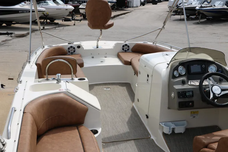 Slide: The Image of 2020 Stingray 212SC boat interior with brown seating and modern dashboard. - 6