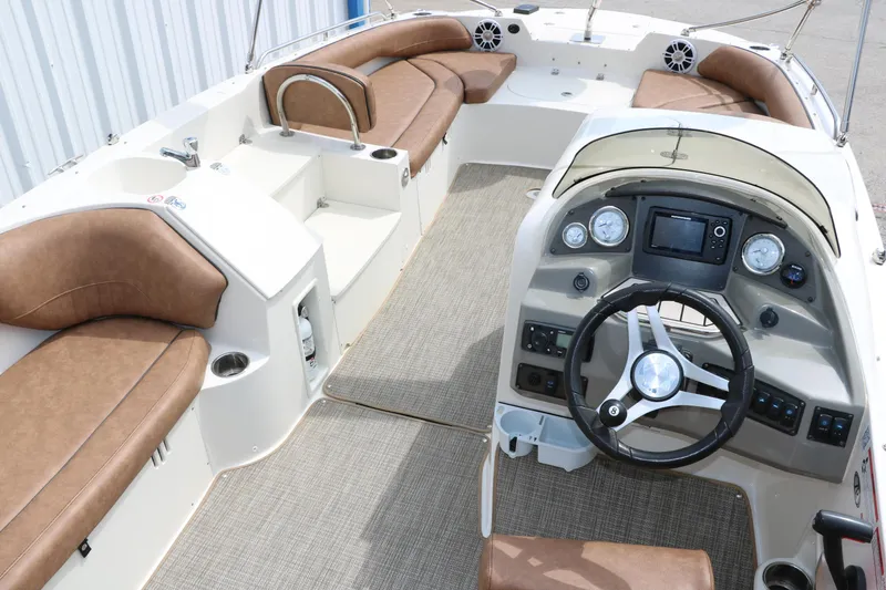 Slide: The Image of 2020 Stingray 212SC boat interior with brown seating and modern dashboard. - 9