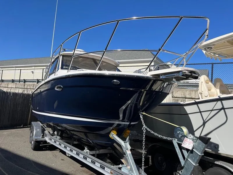 The Image of 2025 Cutwater C-248 C Coupe boat on trailer, blue hull, parked outdoors. - 0