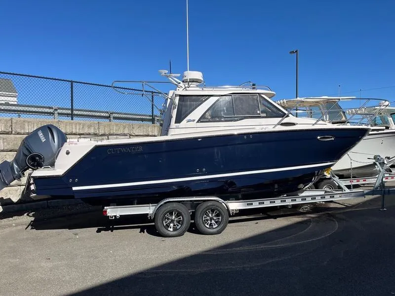 Slide: The Image of 2025 Cutwater C-248 C Coupe boat on trailer, parked outdoors under clear blue sky. - 16