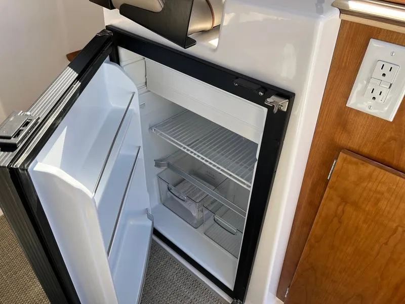 Slide: The Image of Compact refrigerator inside 2025 Cutwater C-248 C Coupe boat, open with shelves visible. - 5