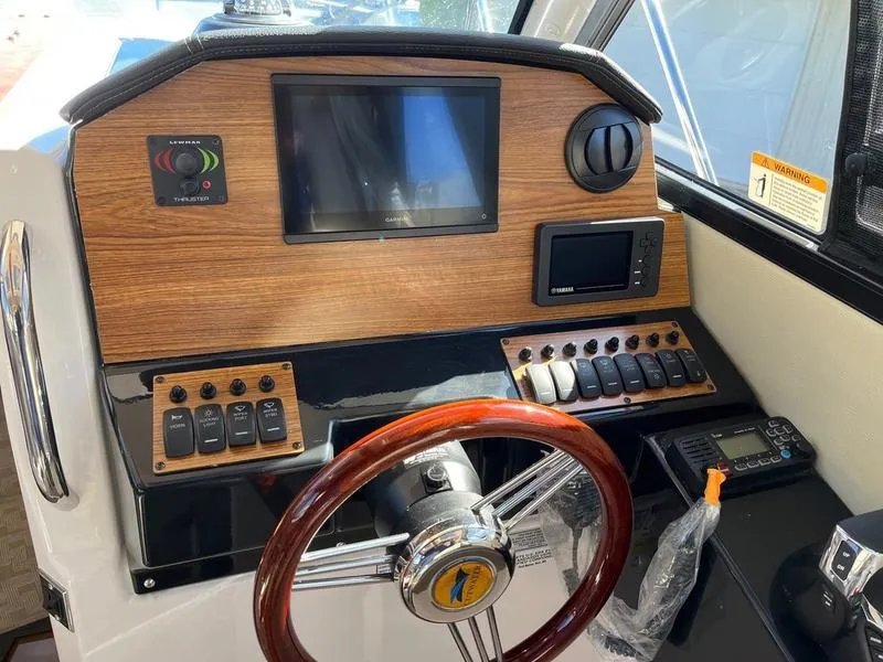 Slide: The Image of 2025 Cutwater C-248 C Coupe helm with wood paneling, steering wheel, and electronic controls. - 9