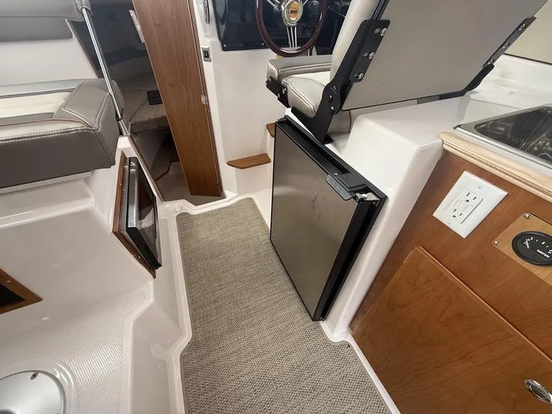 Slide: The Image of Interior of 2025 Cutwater C-248 C Coupe, featuring seating, fridge, and wooden cabinetry. - 14