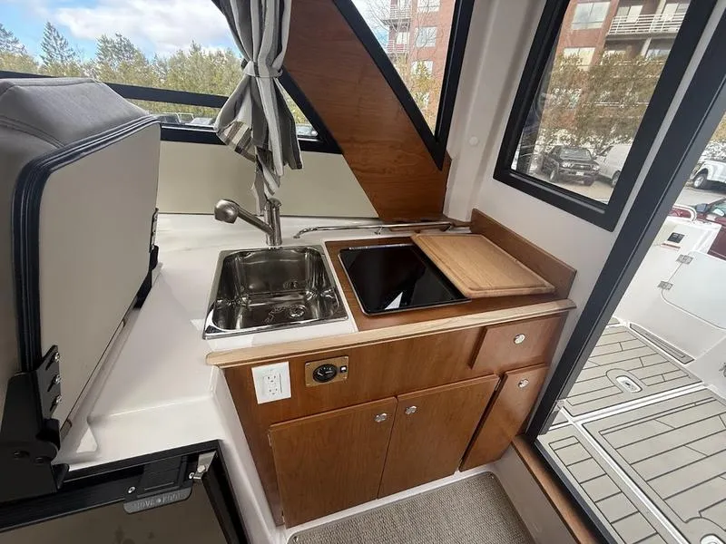 Slide: The Image of Interior of 2025 Cutwater C-248 C Coupe featuring compact kitchen with sink and stove. - 15