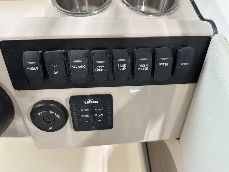 Slide: The Image of Control panel of 2024 Boston Whaler 240 Vantage boat with various switches and cup holders. - 11