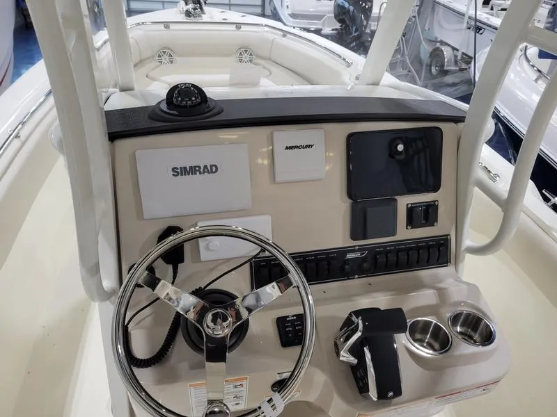 Slide: The Image of 2025 Boston Whaler 230 Outrage boat console with steering wheel and navigation controls. - 11