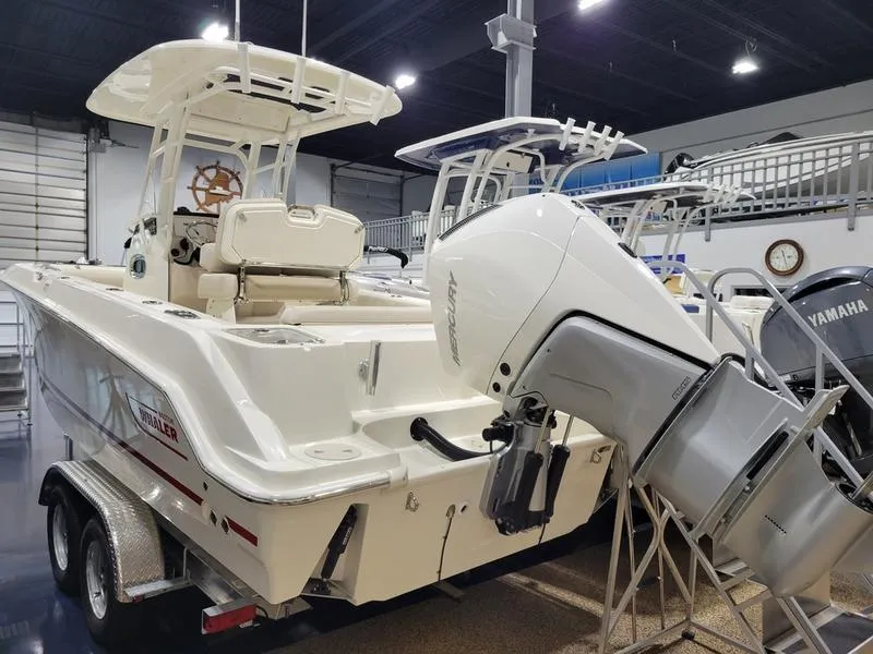 Slide: The Image of 2025 Boston Whaler 230 Outrage boat in showroom, featuring powerful outboard motor. - 3