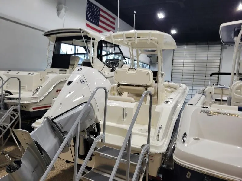 Slide: The Image of 2025 Boston Whaler 230 Outrage boat displayed in showroom with American flag. - 4