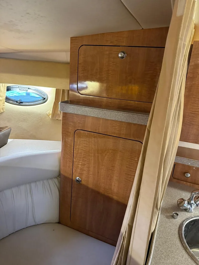 Slide: The Image of 2004 Regal 3260 Commodore cabin interior with wooden cabinets and porthole window. - 34