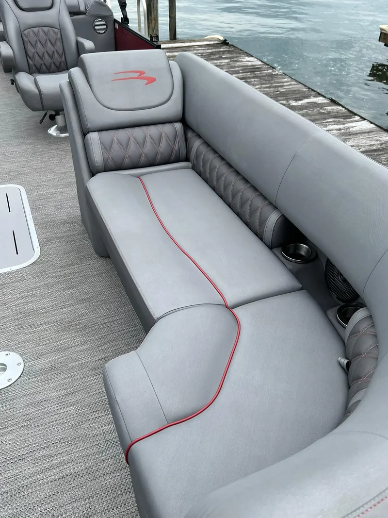 Slide: The Image of 2022 Bennington 24 LXFB boat with luxurious gray seating and red accents. - 13