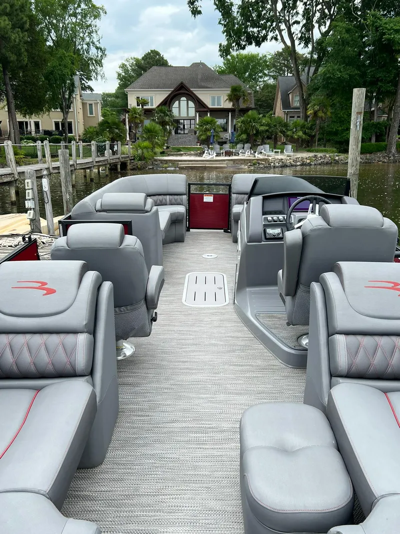 Slide: The Image of 2022 Bennington 24 LXFB pontoon boat with luxurious seating, docked near waterfront homes. - 16