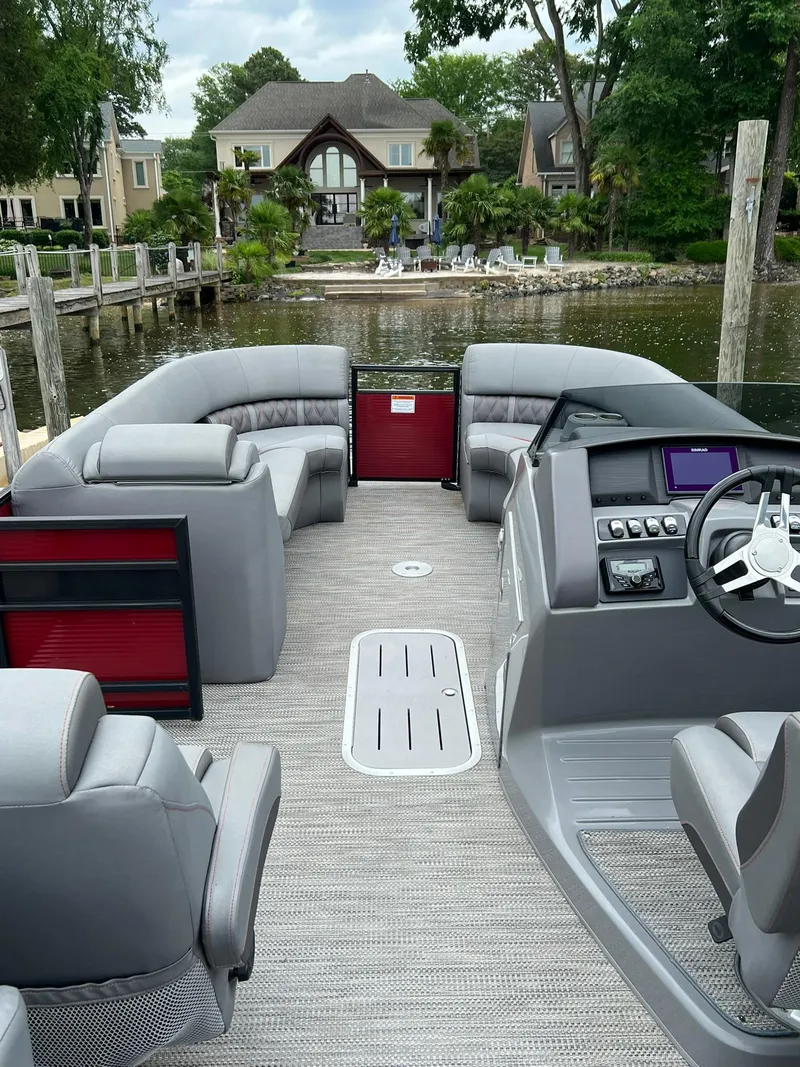 Slide: The Image of 2022 Bennington 24 LXFB pontoon boat with luxurious seating and modern dashboard on a serene lake. - 21