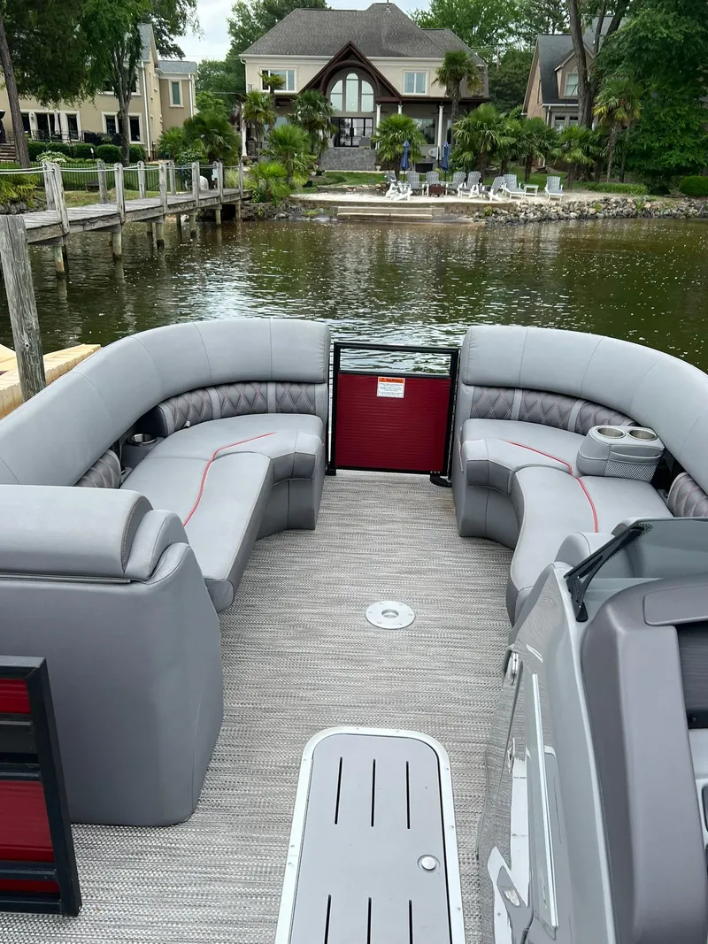 Slide: The Image of 2022 Bennington 24 LXFB pontoon boat with luxurious seating on a serene lake. - 22