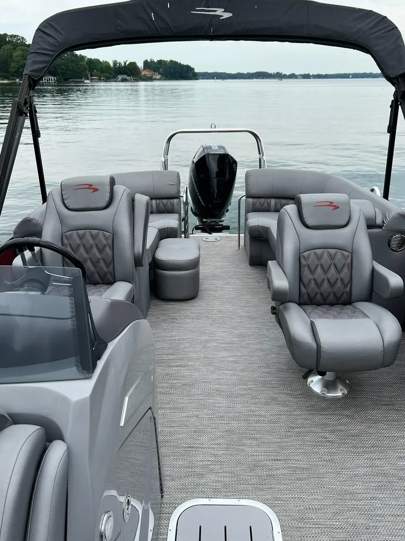 Slide: The Image of 2022 Bennington 24 LXFB pontoon boat with luxurious seating on a calm lake. - 23