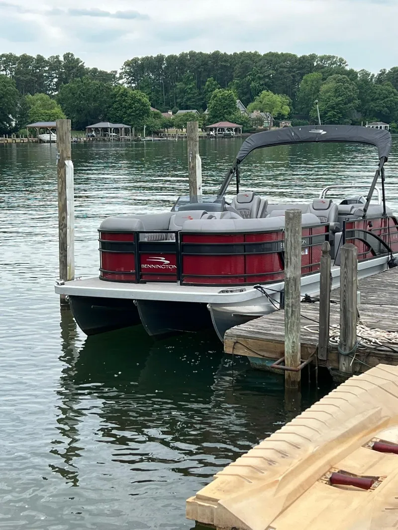 Slide: The Image of 2022 Bennington 24 LXFB pontoon boat docked on a serene lake. - 3