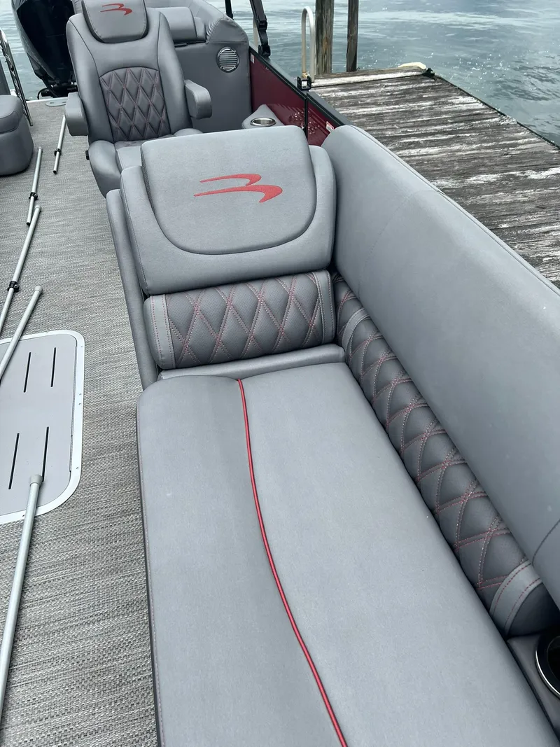 Slide: The Image of 2022 Bennington 24 LXFB boat with luxurious gray seating and red accents. - 8