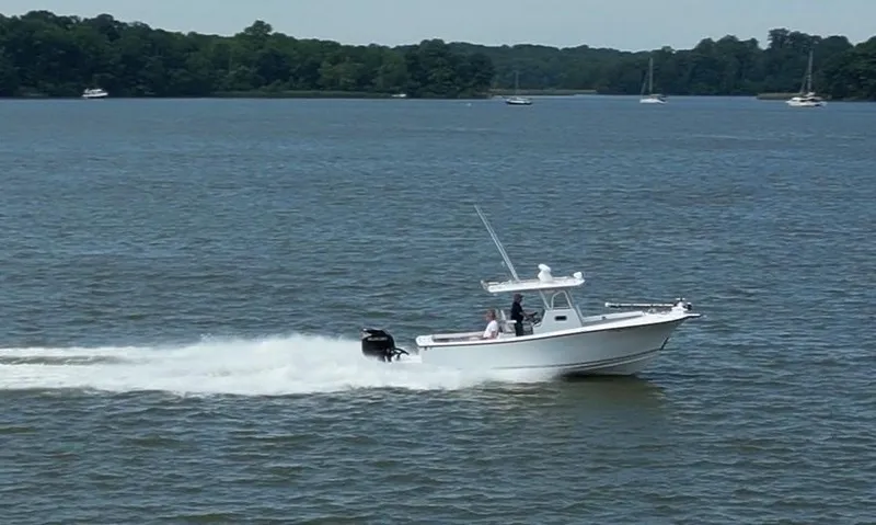 Slide: The Image of A 2017 Custom Carolina Style boat speeding on a lake with trees in the background. - 14
