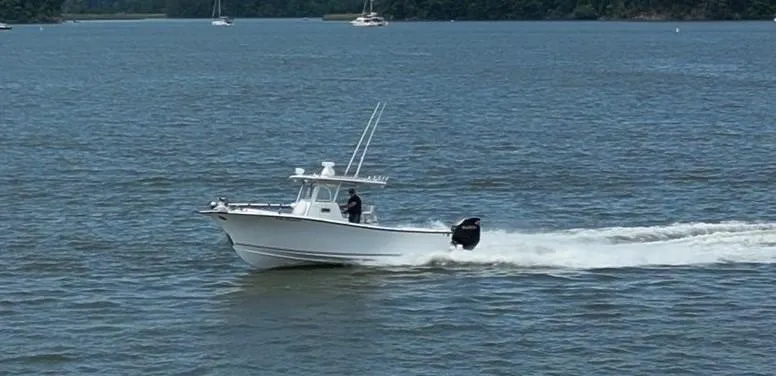 Slide: The Image of A 2017 Custom Carolina Style boat cruising on a lake with trees in the background. - 20