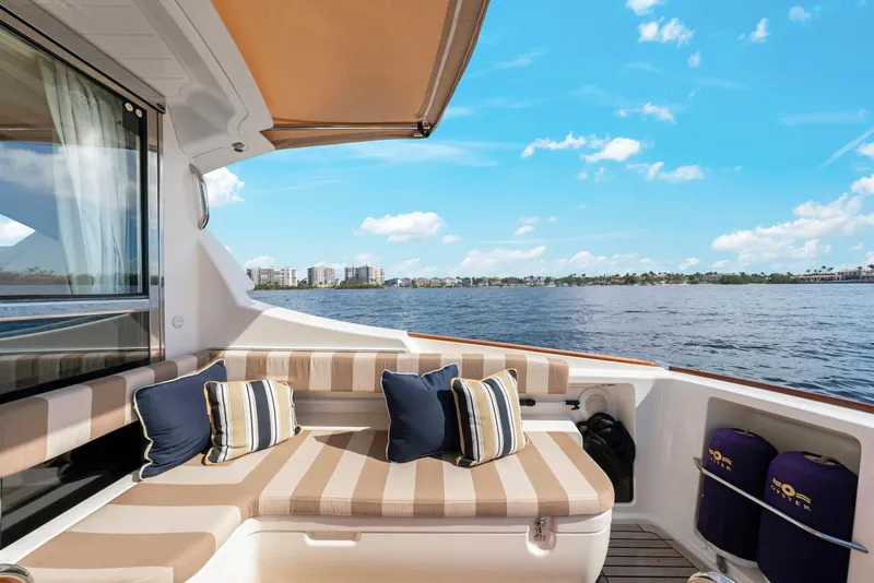 Slide: The Image of Luxurious 2007 Oyster LD43 yacht deck with striped seating, cushions, and scenic waterfront view. - 18