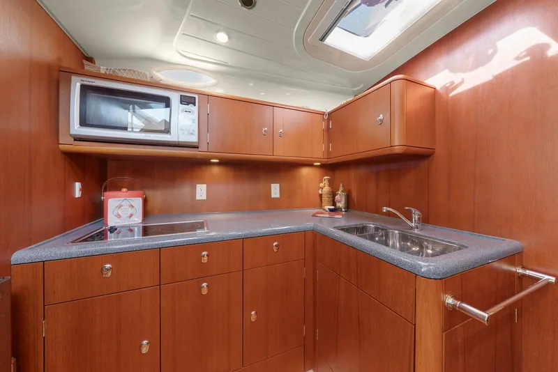 Slide: The Image of 2007 Oyster LD43 yacht kitchen with wood cabinetry, microwave, and sink. - 49