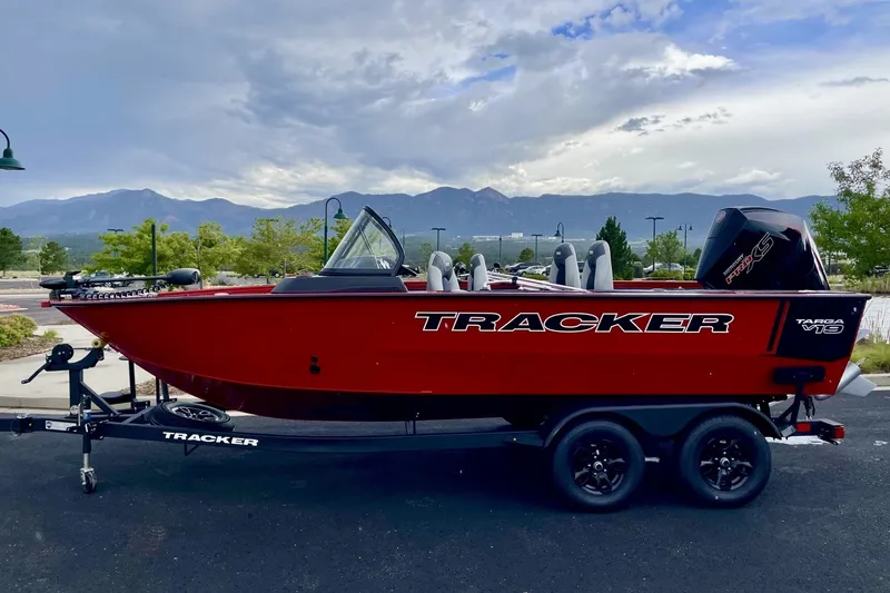 The Image of 2024 Tracker Targa V-19 Combo boat in vibrant red, parked with scenic mountain backdrop. - 0