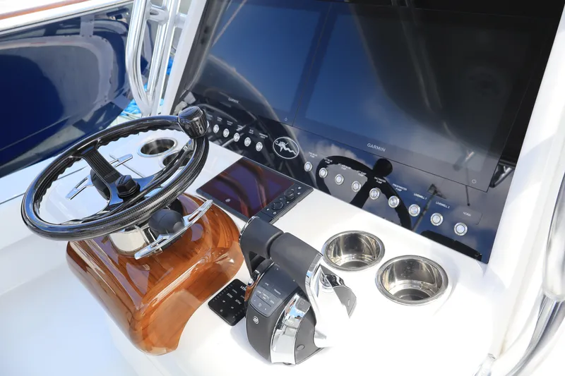 Slide: The Image of 2024 Valhalla Boatworks V-28 helm station with steering wheel, controls, and dual cup holders. - 10