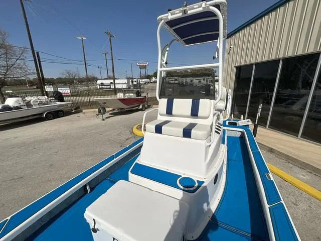 Slide: The Image of 2024 Majek 25 ILLUSION boat with blue and white seating, parked outdoors. - 14