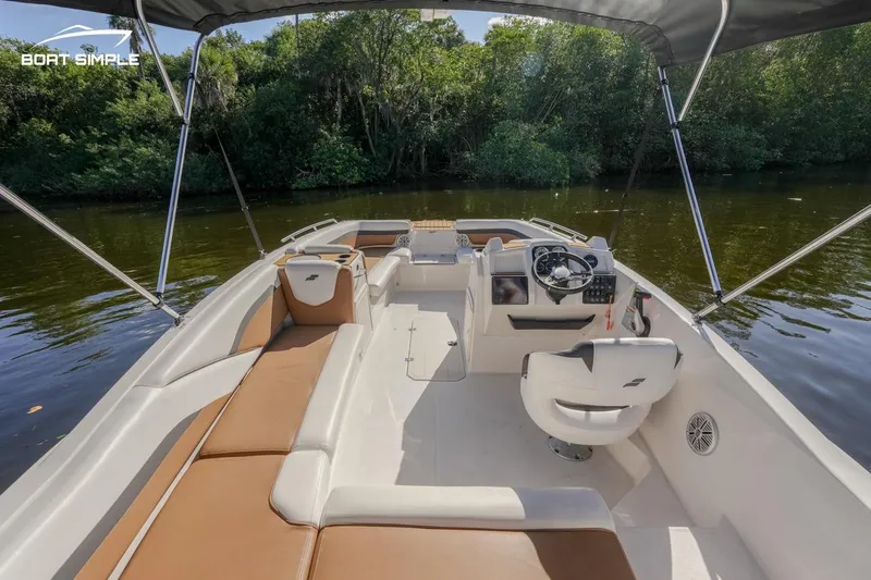 Slide: The Image of 2022 Starcraft SVX 191 OB boat interior with tan seating and canopy on a calm river. - 7