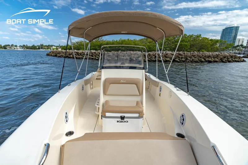 Slide: The Image of 2021 Scout 195 Sportfish boat on water, featuring a beige canopy and seating. - 8