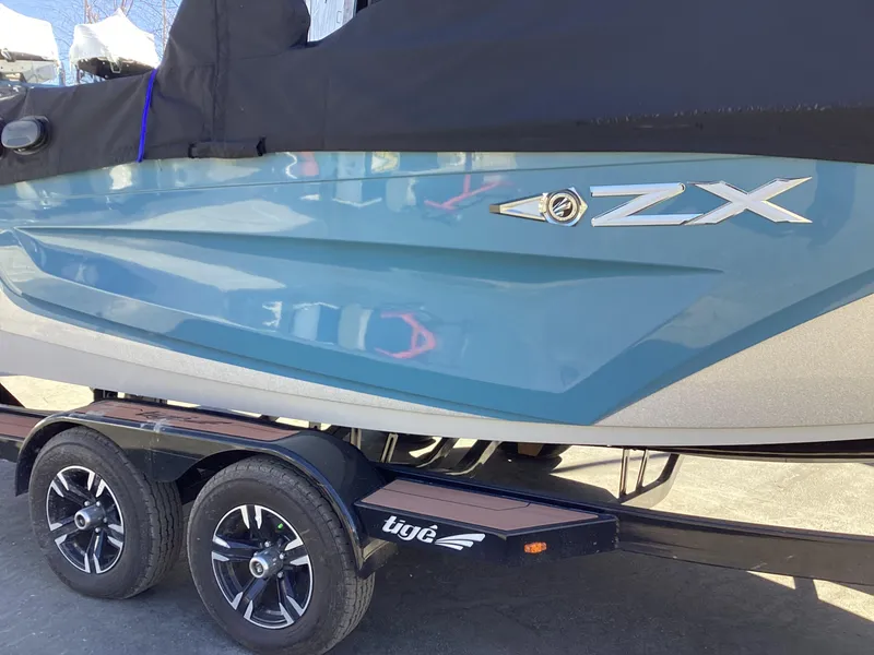 Slide: The Image of 2020 Tigé 21ZX boat on a trailer, side view with cover. - 21