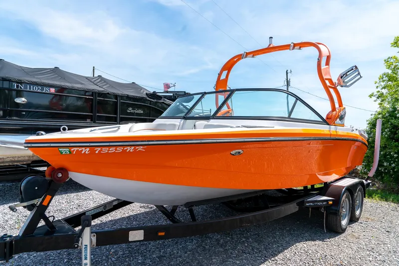 The Image of 2013 Nautique 210 SUPER AIR boat in orange on a trailer. - 1