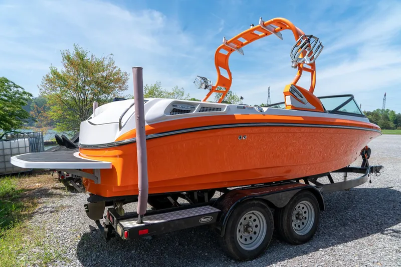 Slide: The Image of 2013 Nautique 210 SUPER AIR boat on a trailer, bright orange exterior. - 11