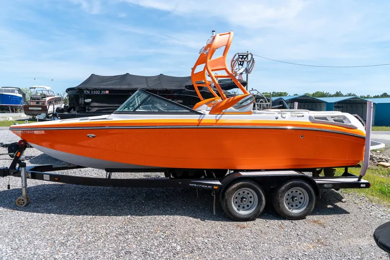 Slide: The Image of 2013 Nautique 210 SUPER AIR boat in bright orange on a trailer. - 3