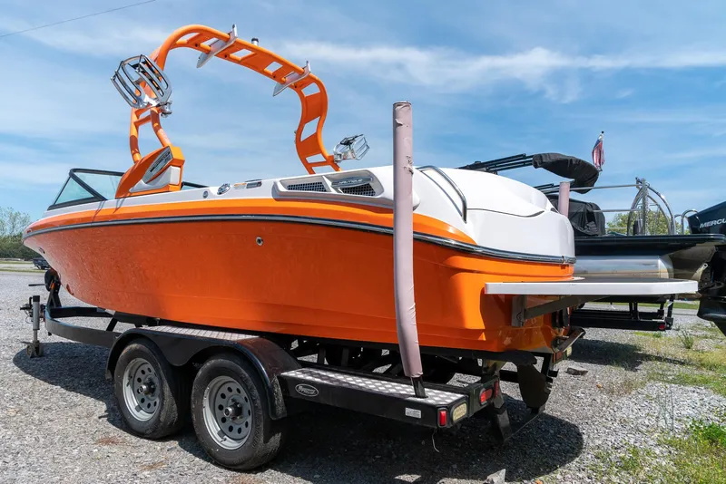 Slide: The Image of 2013 Nautique 210 SUPER AIR boat on trailer, bright orange hull, wakeboard tower. - 5