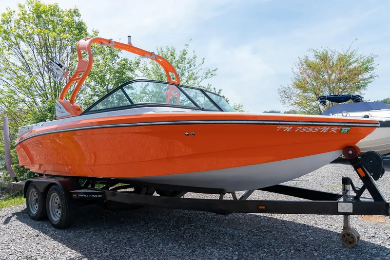 Slide: The Image of 2013 Nautique 210 SUPER AIR boat in orange on a trailer. - 6