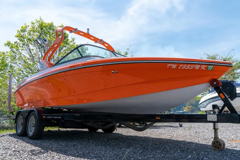 Slide: The Image of 2013 Nautique 210 SUPER AIR boat in vibrant orange on a trailer. - 7